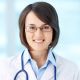 Mujer joven con gafas y bata blanca de doctora, sonriendo y con un estetoscopio alrededor del cuello.